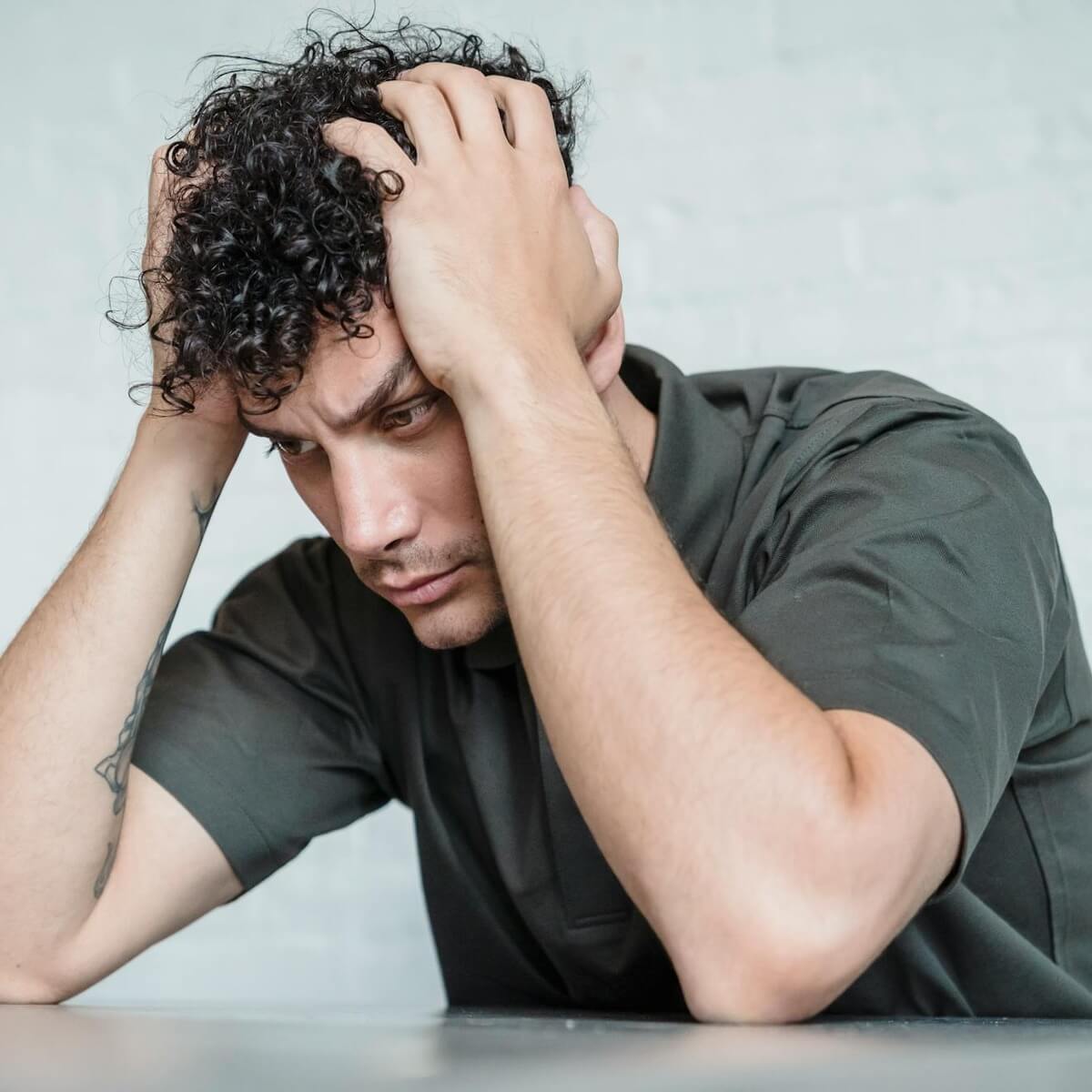 A man sitting at a table with his head in his hands, visibly stressed and overwhelmed