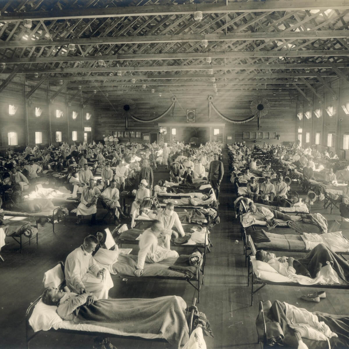 Emergency hospital during the 1918 influenza epidemic at Camp Funston, Kansas, showing rows of sick patients in beds filling a massive hall